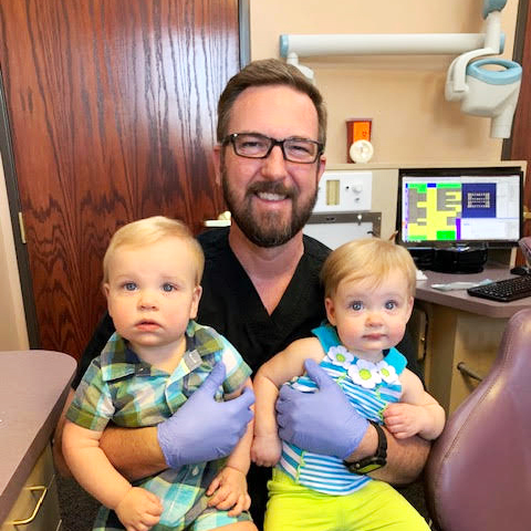 Dr. Joseph C. Creech III smiling holding two little children.